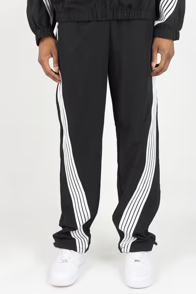 Rebel Minds black crinkled nylon pants featuring white contrast bent stripes and a relaxed fit on a model