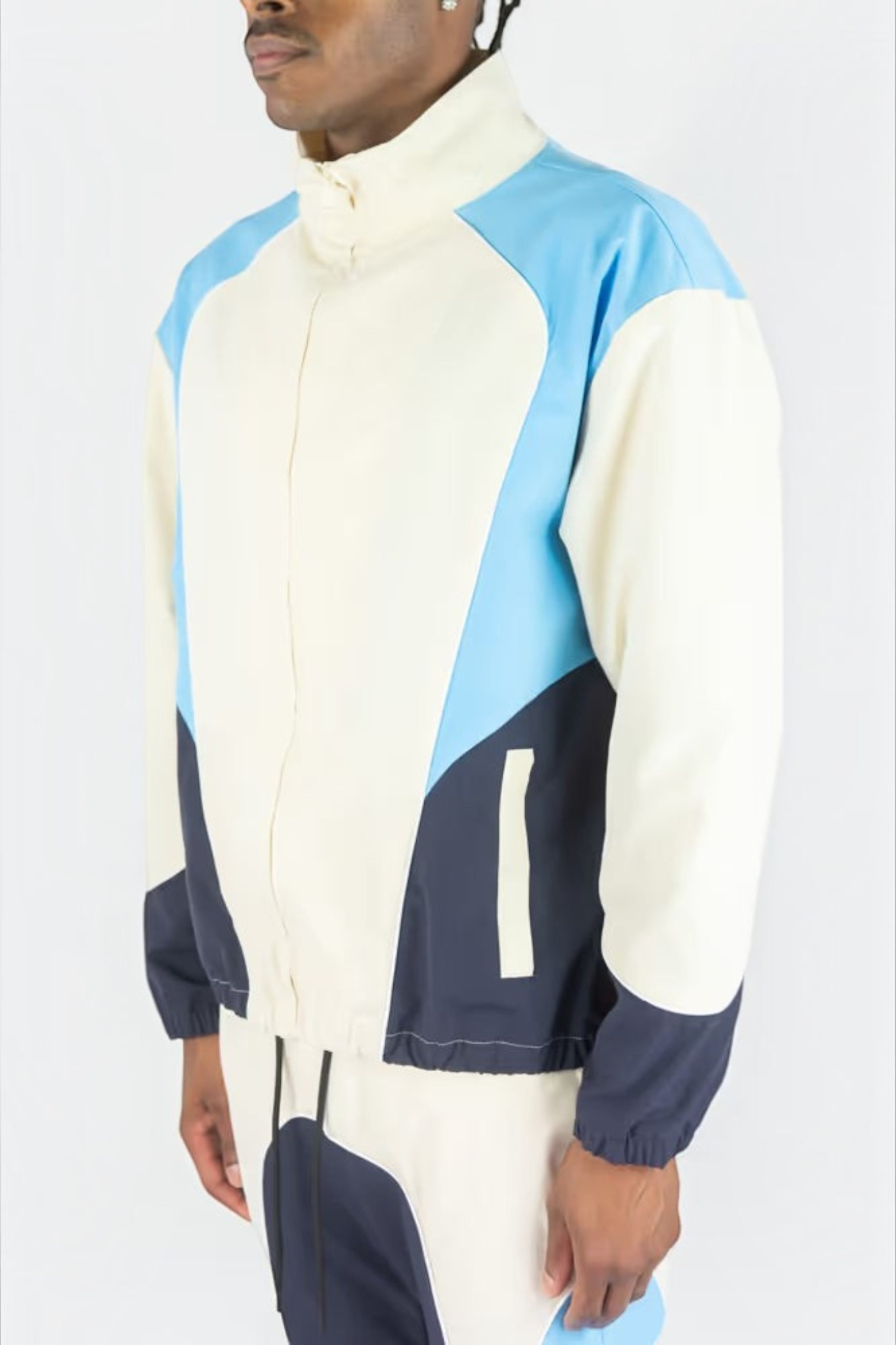 Rebel Minds cream, light blue, and navy ripstop windbreaker jacket with a high collar and matching flare-fit pants.